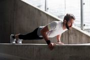 Hipster mit Vollbart, frisch gescheitelt und gegelt, macht Liegestütze auf Beton-Balustrade Hipster mit Vollbart, frisch gescheitelt und gegelt, macht Liegestütze auf Beton-Balustrade
